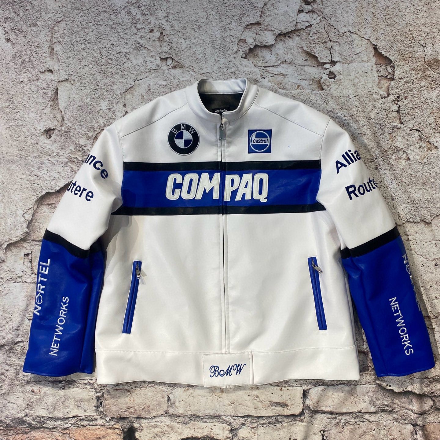 White jacket with blue accents and branding on a textured stone wall background