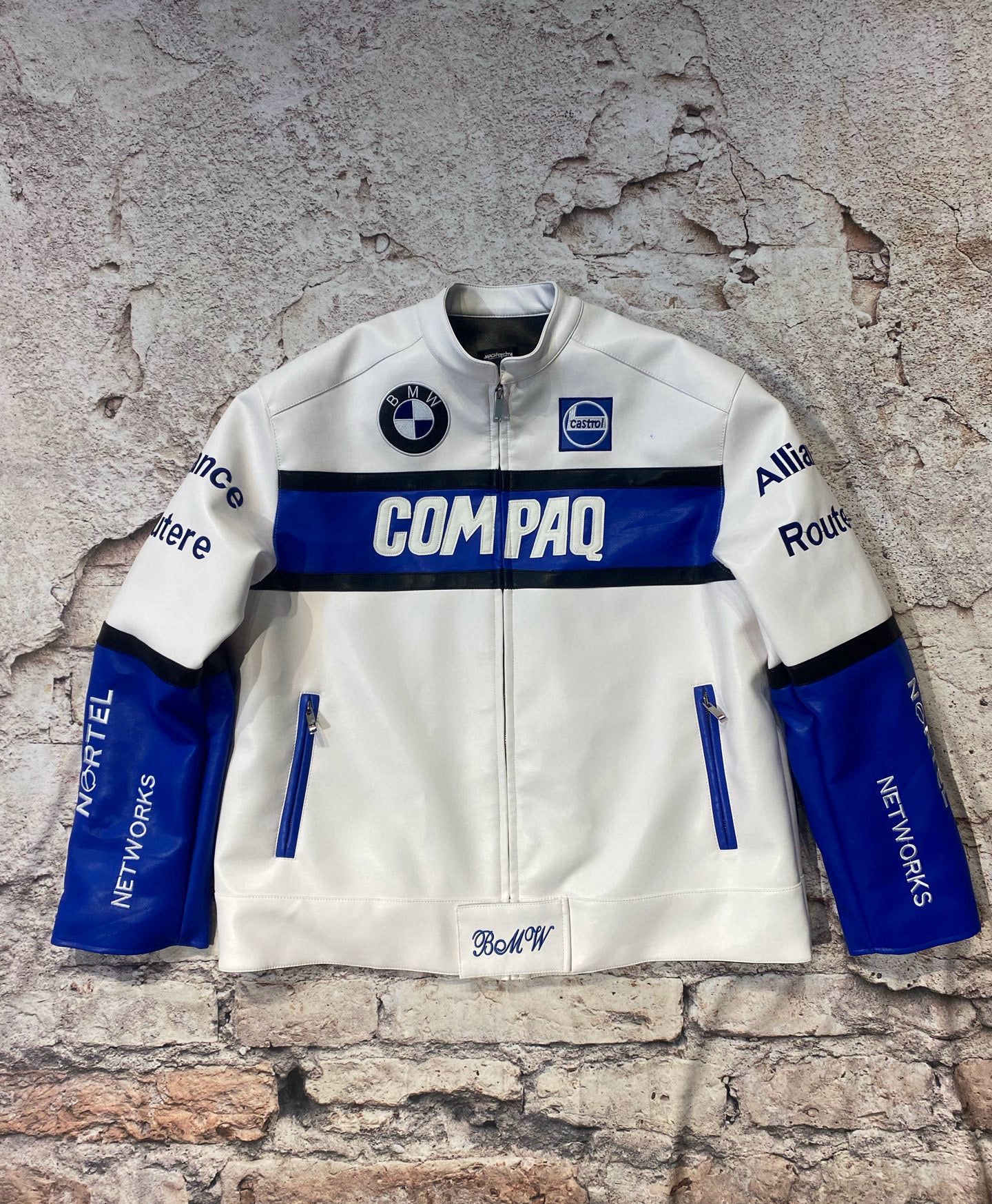 White jacket with blue accents and branding on a textured stone wall background