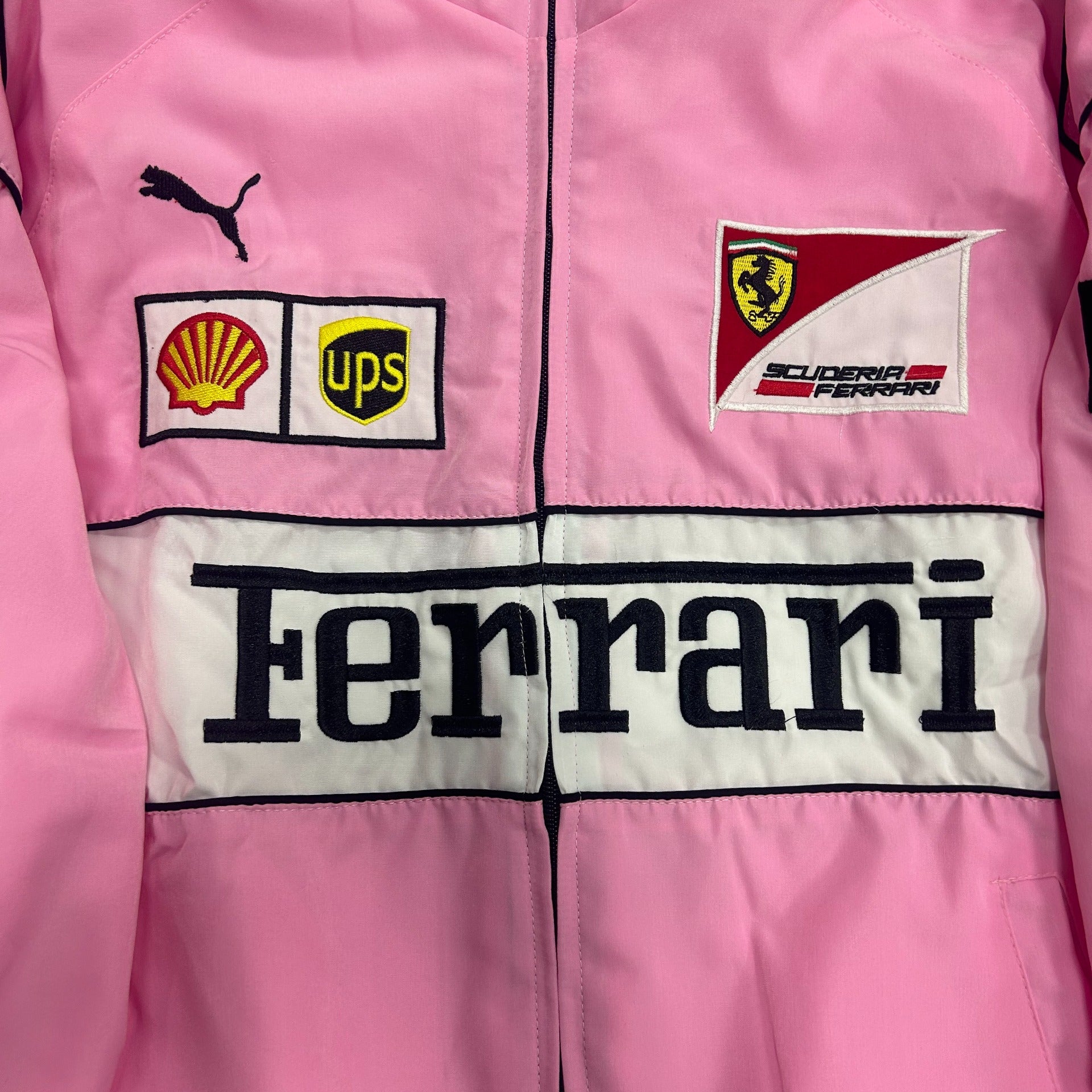 Pink jacket with Ferrari, Puma, UPS, and Shell logos on a checkered background