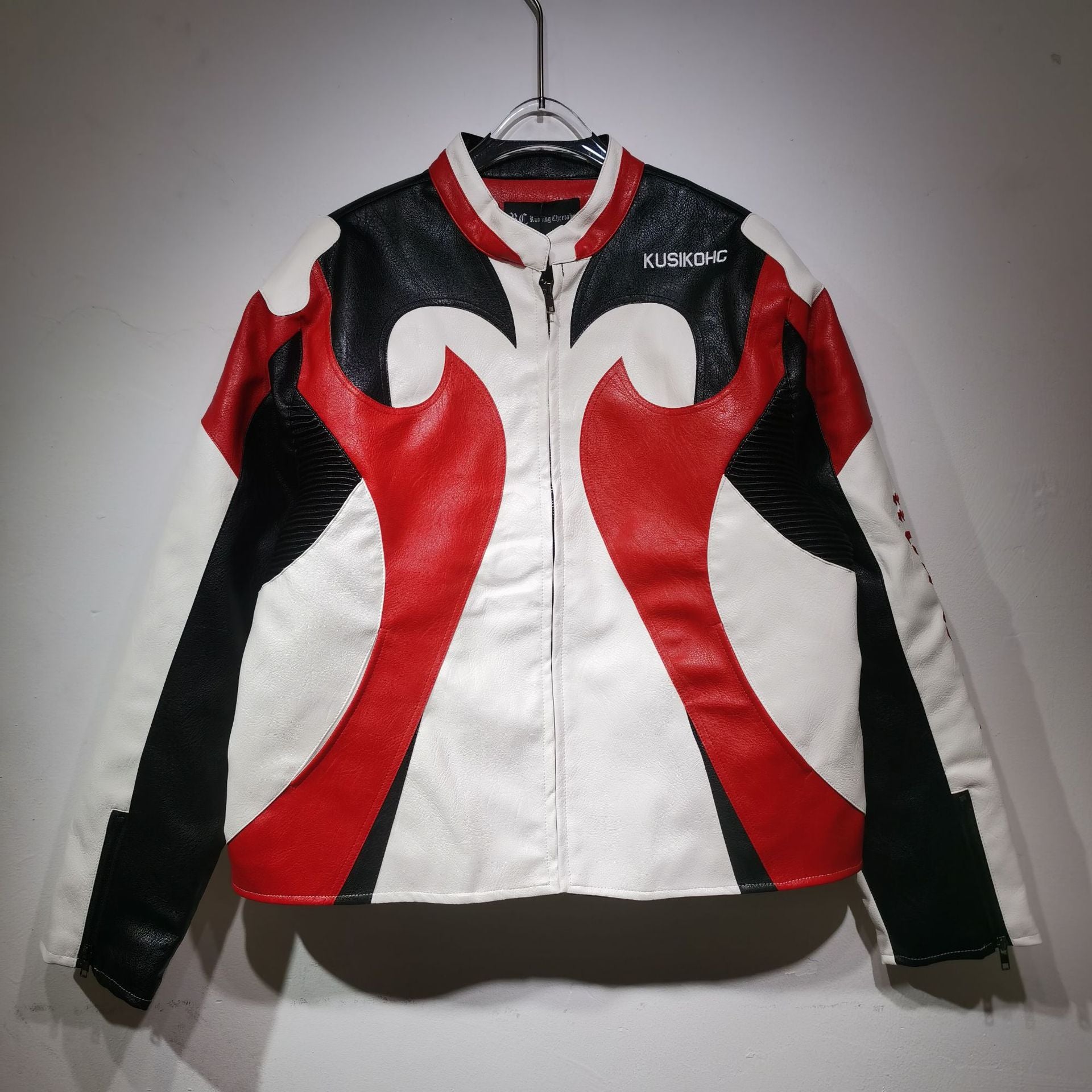 Black, red, and white jacket with flame design on a hanger against a gray background