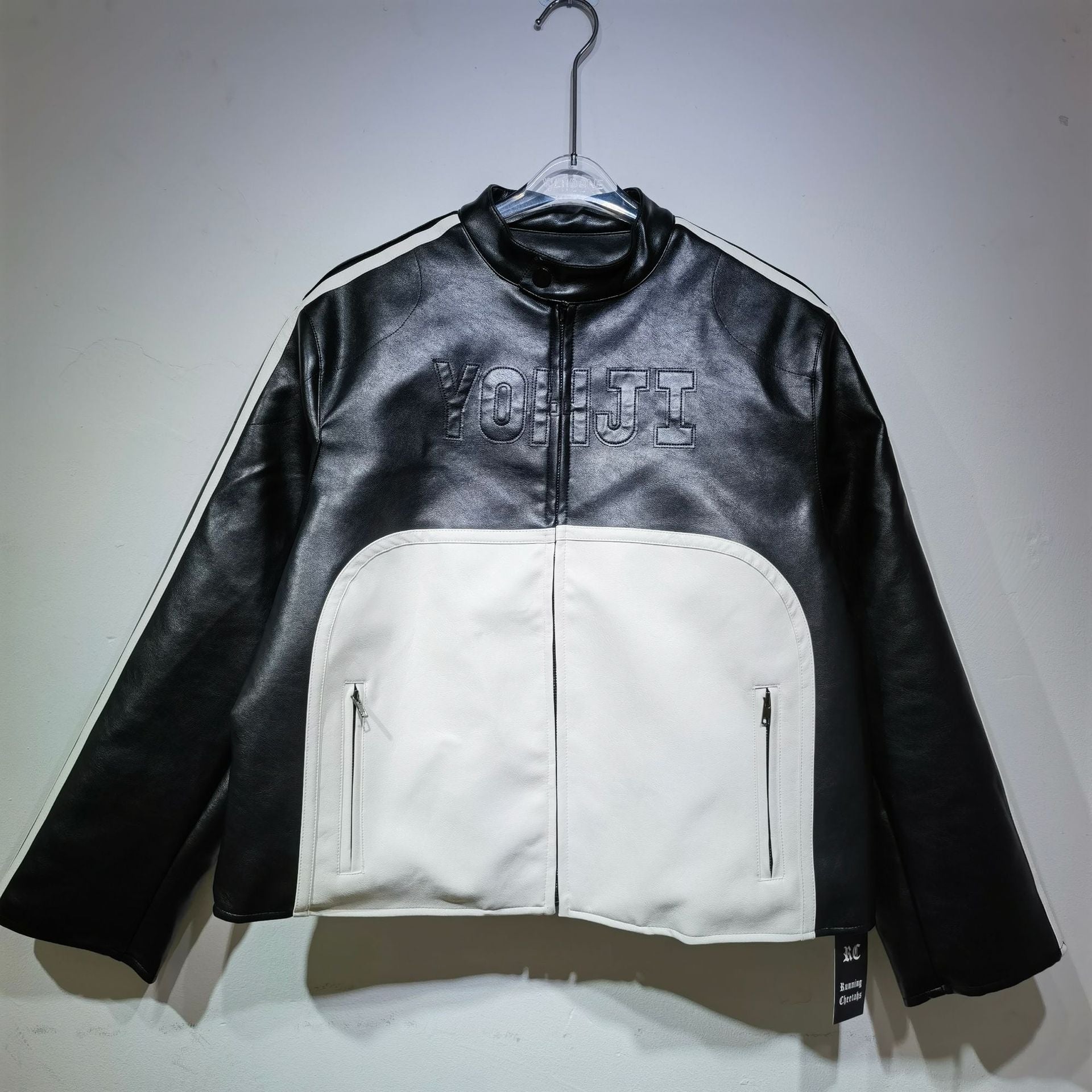Black and white jacket with 'Yohji' branding on a hanger against a plain background